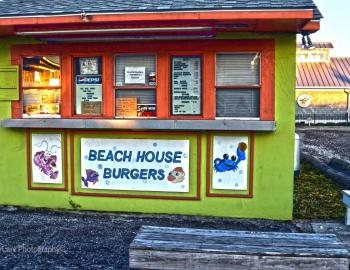 a large permanent green kiosk with four takeout windows and a sign: &quot;Beach House Burgers&quot;