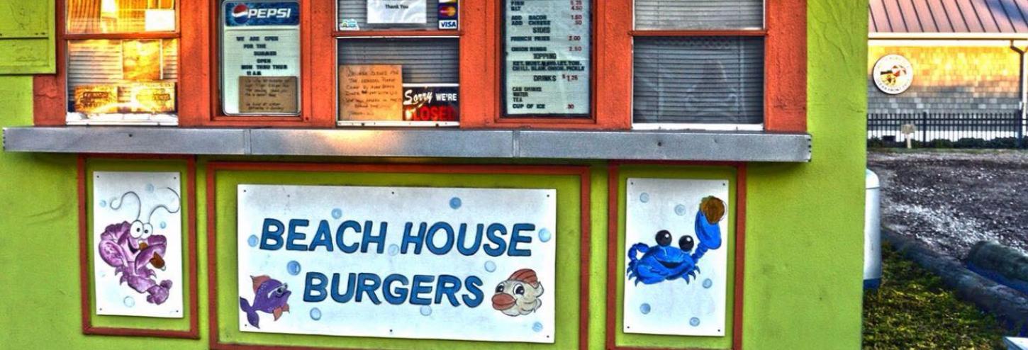 a large permanent green kiosk with four takeout windows and a sign: &quot;Beach House Burgers&quot;