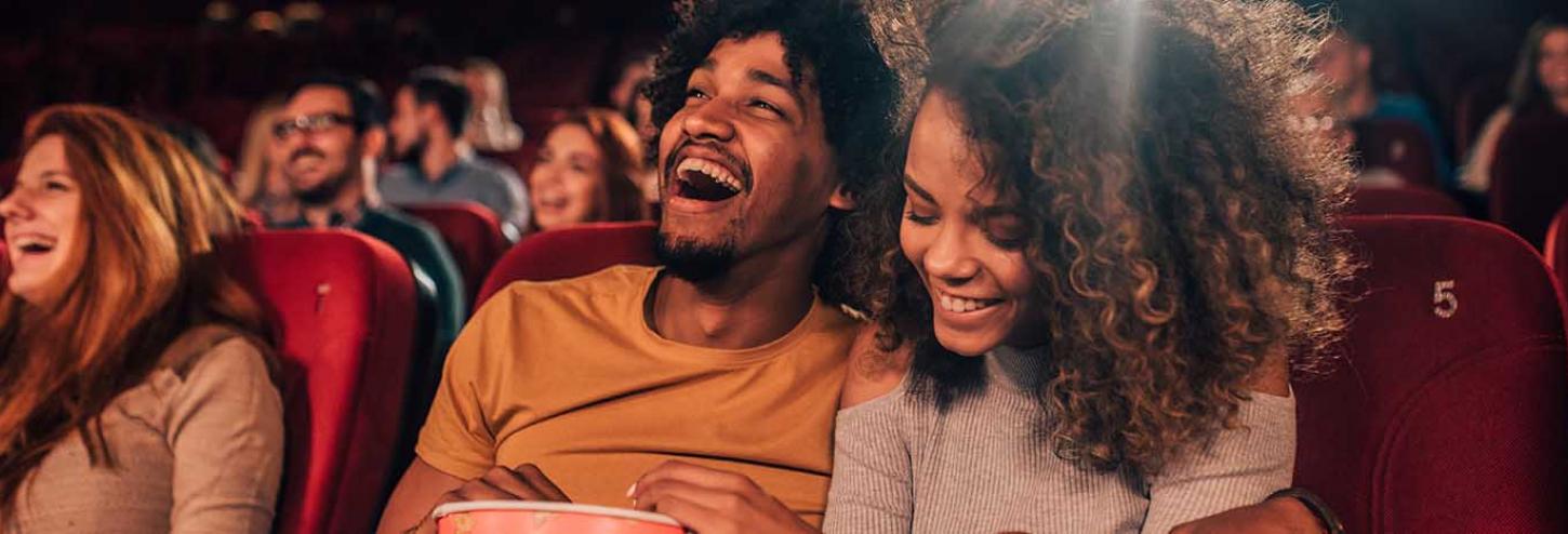 Boyfriend and girlfriend laughing and enjoying a movie together