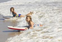 two girls boogie boarding at the beach